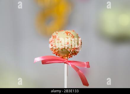 Torta di cioccolato bianco pop decorato con colorfull pasticceria spruzzata su uno sfondo pastello. Concetto di festa Foto Stock