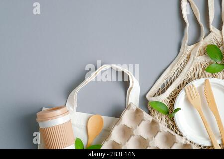 Concetto di shopping a zero sprechi. Vista dall'alto, ovobox ecologico, sacchetto in rete, tazza riutilizzabile su sfondo grigio. Stile di vita sostenibile e senza plastica Foto Stock