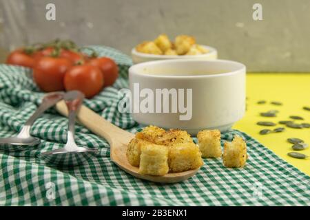 Zuppa di piselli con crostini si erge su un tovagliolo verde, accanto a ci sono pomodori, toast di semi di zucca, tutto si erge sul tavolo giallo Foto Stock