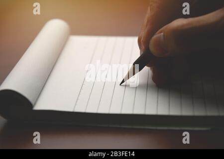 Mano maschio con matita scritta sul notebook. Uomo che lavora in casa Foto Stock