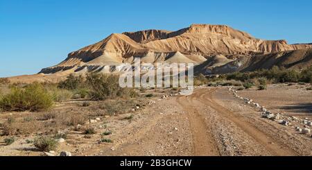 la strada della jeep che attraversa il letto del torrente nahal zin nel negev in israele con le montagne mozzafiato deserto arido e cielo blu sullo sfondo Foto Stock