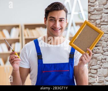 Il riparatore che mette cornice di immagine sulla parete Foto Stock