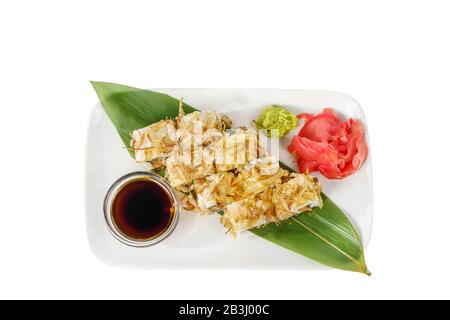 Sushi, panini, uramaki con tonni flakes, avocado, cetrioli, formaggio e salmone, pesce, frutti di mare crudi, salsa di soia, zenzero marinato e wasabi. Cibo su banano Foto Stock