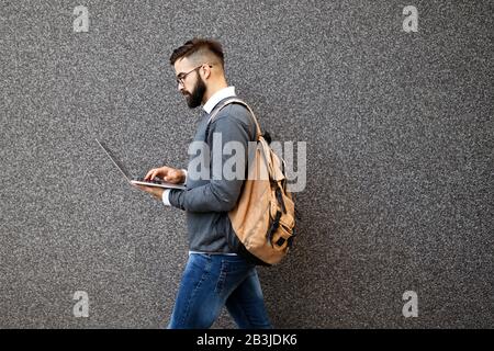 Un uomo bello e sicuro che usa un computer portatile all'aperto Foto Stock