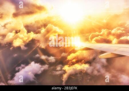 Vista in un'ala splendente dell'aeroplano al tramonto sulle nuvole Foto Stock