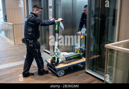 05 marzo 2020, Renania Settentrionale-Vestfalia, Bochum: Un e-scooter è spinto come prova da funzionari della giustizia su un tram da un ascensore del tribunale distrettuale. Due giovani uomini devono essere processati per tentare l'omicidio. Gli uomini di 18 e 22 anni sono accusati di aver gettato lo scooter elettrico su una parete di sicurezza alta due metri in un tunnel di ingresso sulla strada. Di conseguenza, quattro veicoli erano stati coinvolti in un incidente. Foto: Bernd Thissen/Dpa Foto Stock