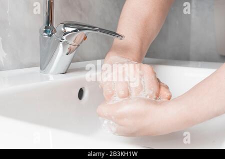 Tecniche efficaci di lavaggio a mano: Strofinare il palmo con la parte posteriore delle dita dell'altra mano. Il lavaggio delle mani è molto importante per evitare il rischio di contagio da parte di coron Foto Stock