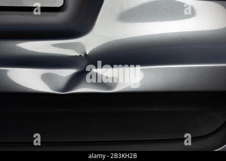 Un'ammaccatura in una piega metallica di un'auto d'argento in luce eccitante. Foto Stock