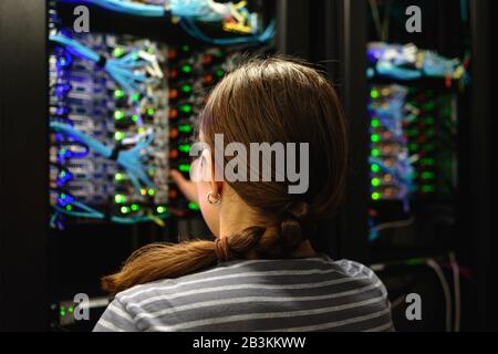 Tecnico di rete Woman vicino al rack server funzionante. Data center di un'azienda IT moderna Foto Stock