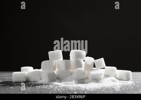 Zollette di zucchero impilati insieme contro uno sfondo nero Foto Stock
