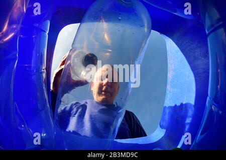 uomo che mette bottiglie di plastica nell'equitazione orientale dello yorkshire riciclaggio wheelie bin ellerton yorkshire regno unito Foto Stock