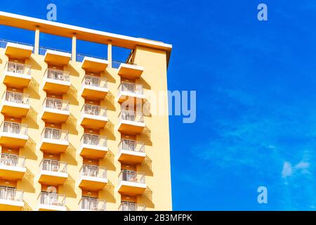 Le camere dell'hotel dispongono di balconi in un edificio moderno. Schema geometrico del balcone sullo sfondo blu del cielo Foto Stock