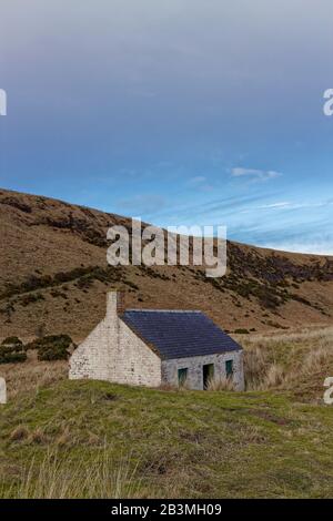 Un cottage Dei Pescatori abbandonati si trova sulla spiaggia di St Cyrus, al riparo dagli elementi delle dune coperte di erba. Foto Stock