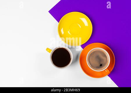 Tazze da caffè colorate e piattini su sfondo colorato e vivace. Foto creativa. Foto Stock