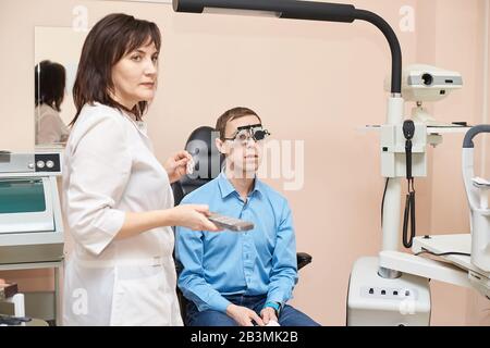 medico oftalmologo in laboratorio di esame ottico con paziente maschile. Uomini occhio Foto Stock