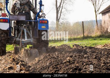 Il trattore arows un campo nella molla accompagnato dai ruscelli preparati per piantare campo agricolo di verdure Foto Stock
