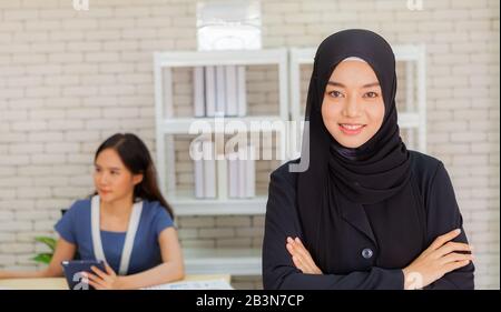 Due businesswomen musulmani stanno discutendo i guadagni dell'azienda felicemente nell'ufficio moderno. Foto Stock