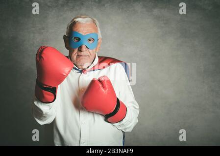 Super nonno, uomo anziano vestito da supereroe su sfondo grigio Foto Stock