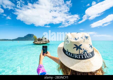 Donna che fotografa la laguna tropicale e Crystal Rock con smartphone, la Gaulette, le Morne Brabant, Mauritius, Oceano Indiano, Africa Foto Stock