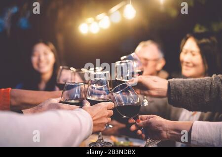 Buona famiglia che si rallegrano con il vino rosso a cena riunione in giardino - Senior divertirsi tostare gli occhiali da vista e mangiare insieme all'aperto Foto Stock