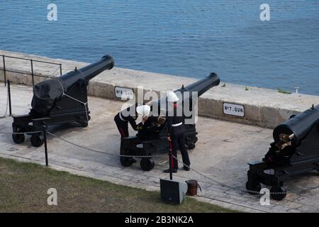 Valleta Malta - 8 febbraio 2020: Soldati che si preparano a sparare cannone con i Giardini di Barakka superiori sullo sfondo Foto Stock