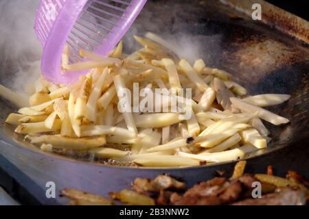 Messicano all'aperto carrello alimentare friggere patatine fritte dopo la carne in padella in una fiera di Carnevale Foto Stock