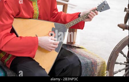 Il musicista suona uno strumento musicale folk russo, una balalaika, in un antico costume nazionale Foto Stock
