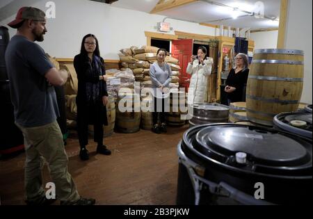 Un operaio che introduce la procedura di distillazione del whisky di borbonio del Tennessee fatto nella distilleria di H Clark ai visitatori asiatici.W.Thompson's Station.Tennessee.USA Foto Stock