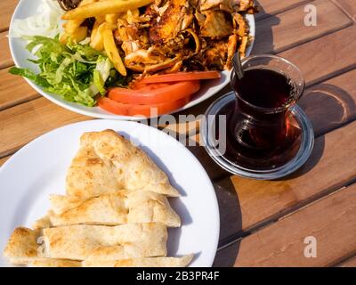 Tradizionale cucina turca, pollo Doner kebab con patatine fritte, pomodori, cipolla e insalata e tè turco Foto Stock