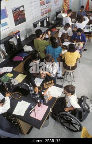 Austin, Texas USA, circa 1997: Il ragazzo handicappato in sedia a rotelle partecipa agli esperimenti di laboratorio con i compagni di classe durante la classe di biologia della scuola superiore. ©Bob Daemmrich Foto Stock