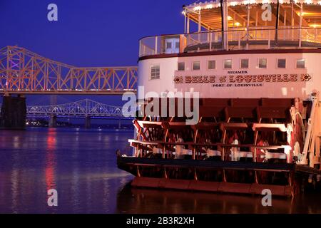 Vista al crepuscolo della storica nave fluviale a pale della Belle of Louisville che attracca sulla riva del Louisville Waterfront Park con il fiume Ohio e il George Rogers Clark Memorial Bridge nel retro.Louisville.Kentucky.USA Foto Stock