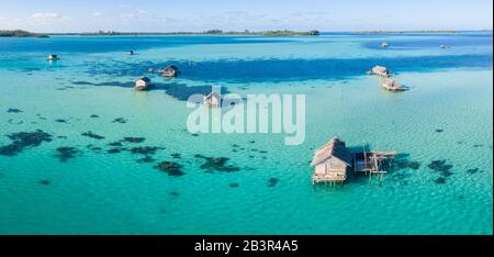 Una vista dall'alto mostra un rustico villaggio indonesiano di pescatori costruito su una barriera corallina vicino a remote isole tropicali nel Mare di Halmahera. Foto Stock