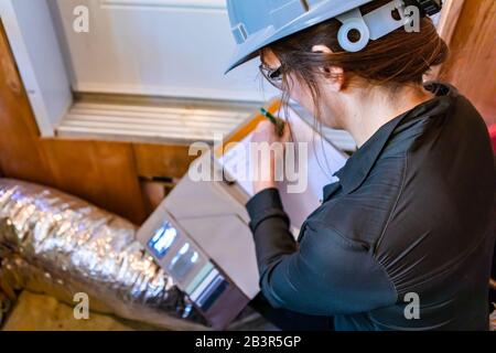 fuoco selettivo vista posteriore di ispettore donna prendere appunti, con incompiuta condotta di aerazione isolato in alluminio e lana di roccia in background. Foto Stock