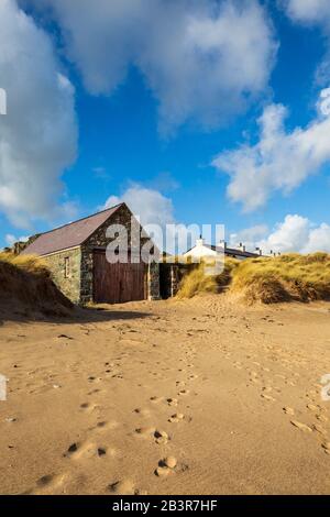 La casa Lifeboat e tetti dei cottage bianchi del pilota dalla spiaggia sull'isola di Llanddwyn, Anglesey Foto Stock