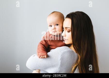 Madre felice che tiene in su la sua ragazza del bambino. Giovane madre bella tiene il suo bambino e coccole, concetto di maternità Foto Stock