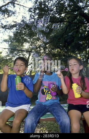 Austin Texas USA, circa 1994: Bambini di otto e nove anni che soffiano bolle all'aperto. SIGNOR ©Bob Daemmrich Foto Stock