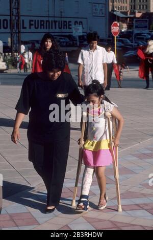 San Antonio, Texas USA: Il bambino ispanico con la gamba in un cast usa stampelle sul marciapiede della città. ©Bob Daemmrich Foto Stock