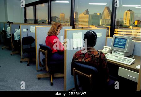 Austin Texas USA: I telemarketers usano le cuffie per fare le chiamate dai cubicoli al centro di vendite della carta di credito. Bob Daemmrich Foto Stock