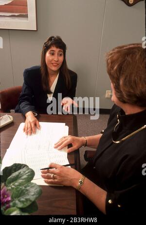 Austin Texas USA, circa 1993: Direttore del personale femminile conduce un colloquio di lavoro con la giovane ispanica di persona in ufficio. ©Bob Daemmrich Foto Stock