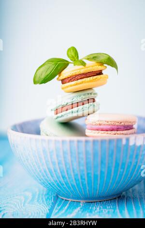 Coppa blu di macaroni colorati francesi o macaron su sfondo di legno Foto Stock