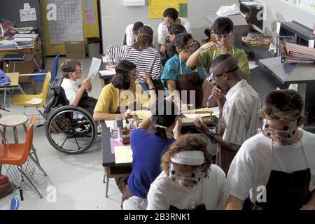 Austin, Texas USA, circa 1997: Il ragazzo handicappato in sedia a rotelle partecipa agli esperimenti di laboratorio con i compagni di classe durante la classe di biologia della scuola superiore. ©Bob Daemmrich Foto Stock