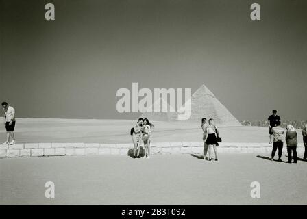 Fotografia di viaggio in bianco e nero - turisti alla Piramide di Khafre e la Grande Piramide alle Piramidi di Giza Cairo in Egitto in Nord Africa Foto Stock