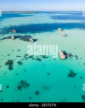 Una vista dall'alto mostra un rustico villaggio indonesiano di pescatori costruito su una barriera corallina vicino a remote isole tropicali nel Mare di Halmahera. Foto Stock