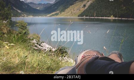 Hiker prendere una pausa seduto vicino al lago di Oule nella valle di Aure in Haute-Bigorre nel dipartimento degli alti Pirenei in Francia Foto Stock