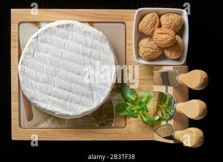 formaggio camambert con noci e basilico su tagliere di legno. Foto Stock
