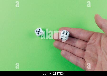 primo piano di mano di uomo che rotola dadi su tavola verde, essendo fortunato e vincente concetto Foto Stock