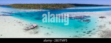 Una vista dall'alto mostra un rustico villaggio indonesiano di pescatori costruito su una barriera corallina vicino a remote isole tropicali nel Mare di Halmahera. Foto Stock