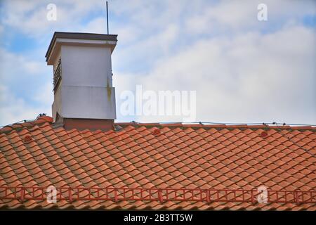 Le righe di sovrapposizione delle tegole rosse tetto con camini in Polonia, colmo di materiale di pannellizzazione modello regolare lo sfondo in orientamento orizzontale, nessuno. Foto Stock