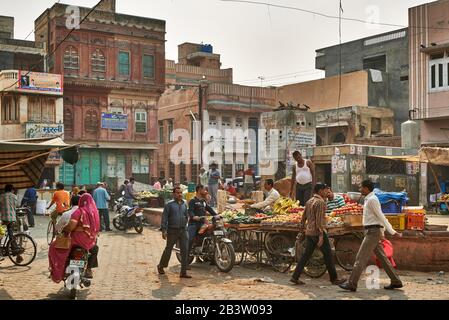 Gente colorata vestita alla stalla di mercato con frutta e verdure a Bikaner, Rajasthan, India Foto Stock