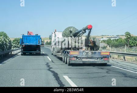 Siviglia; Spagna - 31st maggio 2019: Camion per impieghi gravosi che trasporta un grosso esercito canon. Convoglio stradale con veicoli militari parte per la mostra delle forze armate. Foto Stock